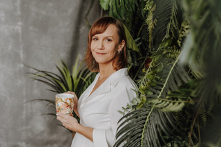 Autorin Nina Waldkirch mit Kaffetasse in der Hand vor Palmen