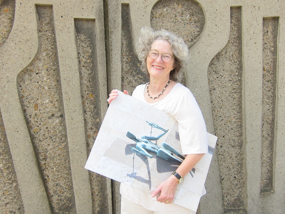 Autorinnenfoto von Bärbel Mäkeler, die ein Bild von Kampmanns Justitia unter den Arm geklemmt hat