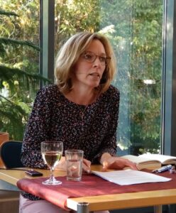 Die Autorin Nicci Schmieder bei einer Lesung mit aufgeschlagenem Buch vor sich