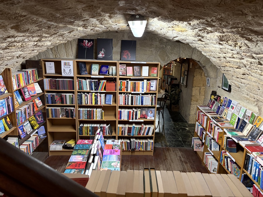 Buchhandlung in Montpellier in einem gemauerten Kellerraum mit gewölbter Decke. Der ganze Raum leuchtet in bunten Farben dank der Rückseiten der Bücher, überall stehen Regale und Auslagen. 