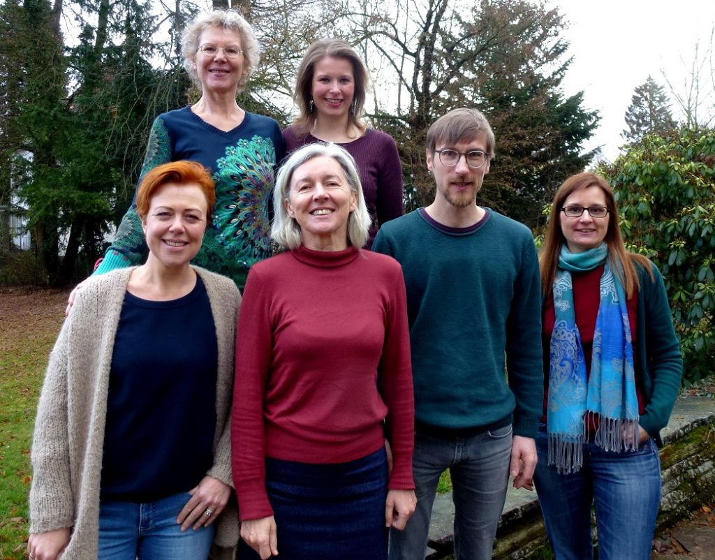 Gruppenfoto des K-Teams 2019, sechs Menschen mit breitem Lächeln vor einem Wald