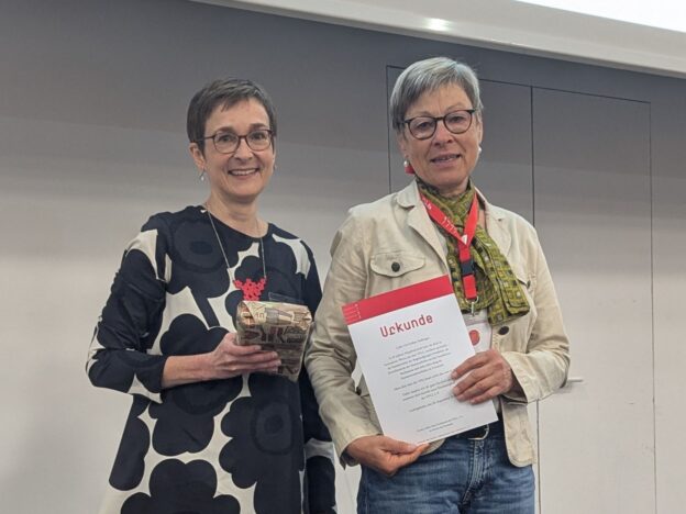 Zwei Frauen nebeneinander: Claudia Lüdtcke steht links, neben ihr Ute Gräber-Seißinger, die eine Urkunde in der Hand hält mit VFLL-Logo